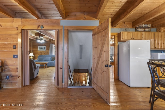 kitchen with wood ceiling, white refrigerator, beamed ceiling, wood walls, and ceiling fan