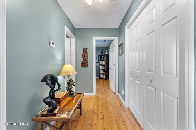 hall with a textured ceiling and light hardwood / wood-style floors