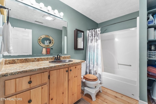 full bathroom featuring toilet, hardwood / wood-style flooring, shower / bath combo with shower curtain, a textured ceiling, and vanity