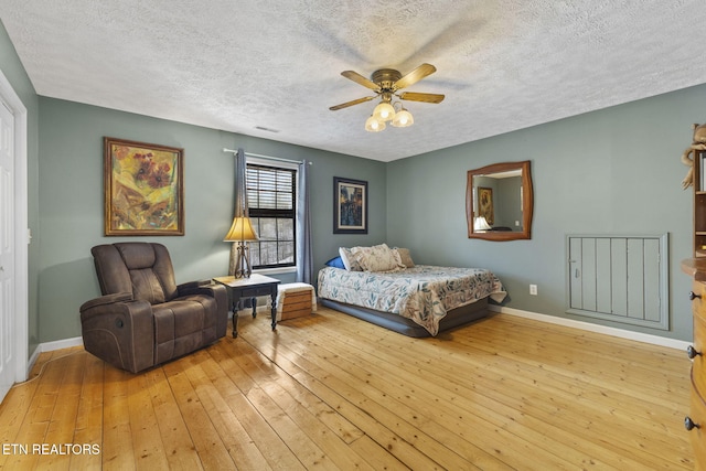 bedroom with a textured ceiling, ceiling fan, and light hardwood / wood-style flooring