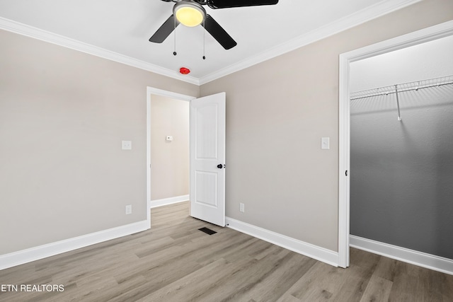 unfurnished bedroom with crown molding, ceiling fan, a closet, and light wood-type flooring