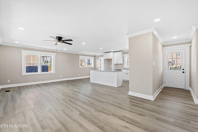 unfurnished living room featuring ceiling fan, ornamental molding, and light hardwood / wood-style flooring