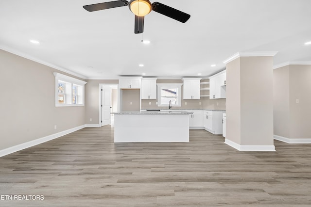 kitchen featuring crown molding, light stone countertops, white cabinets, and light wood-type flooring