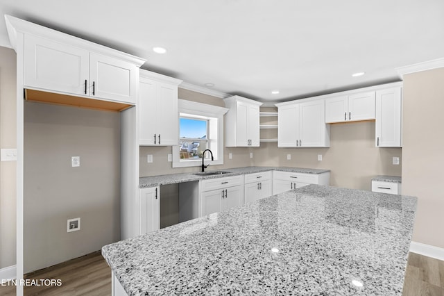 kitchen with light hardwood / wood-style flooring, sink, a kitchen island, and white cabinets