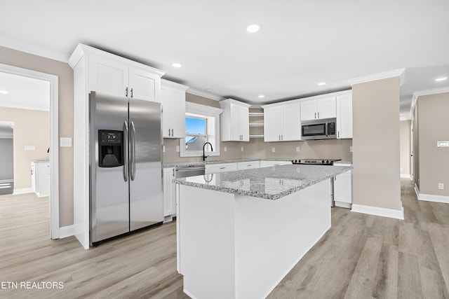 kitchen with light stone countertops, a center island, white cabinets, and appliances with stainless steel finishes