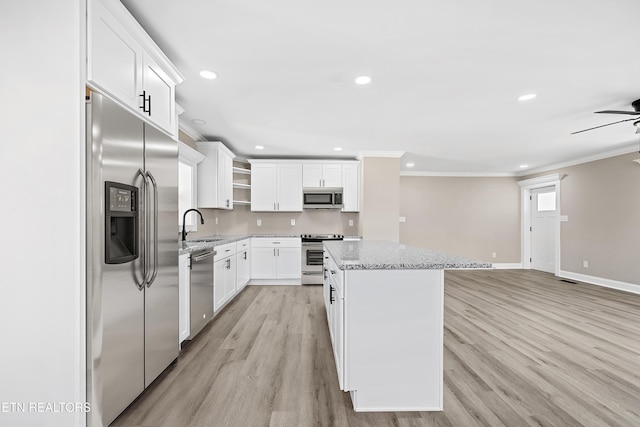 kitchen featuring crown molding, stainless steel appliances, light stone counters, white cabinets, and a kitchen island