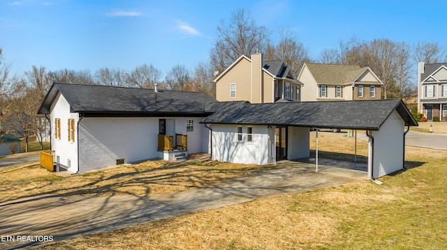 rear view of house featuring a carport and a lawn