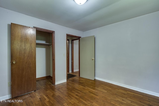 unfurnished bedroom with a closet and dark hardwood / wood-style flooring