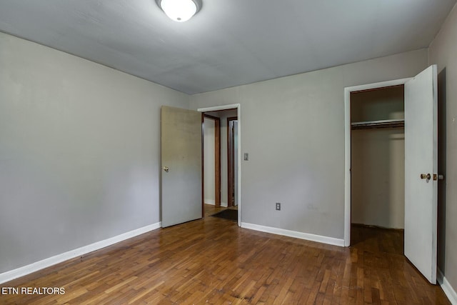 unfurnished bedroom with a closet and dark hardwood / wood-style floors