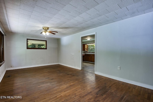 unfurnished room featuring ceiling fan, a wealth of natural light, dark hardwood / wood-style flooring, and sink