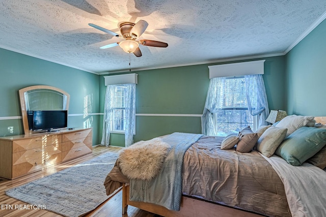 bedroom featuring a textured ceiling, ornamental molding, light hardwood / wood-style floors, and ceiling fan