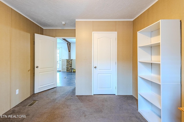 interior space featuring ornamental molding, a textured ceiling, and carpet flooring