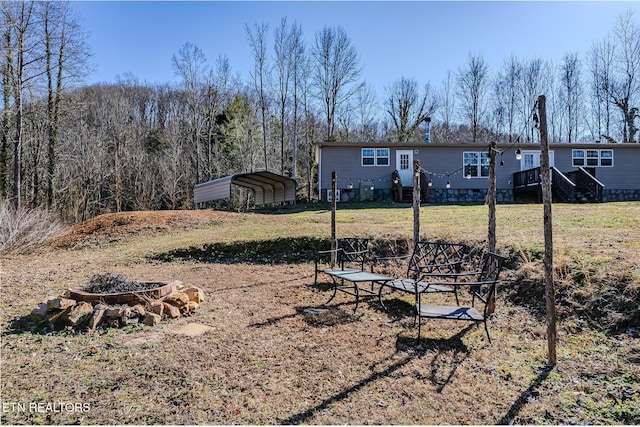 view of yard featuring a fire pit and a carport