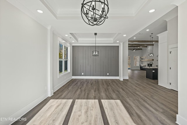 interior space featuring ceiling fan with notable chandelier, a tray ceiling, dark hardwood / wood-style flooring, and ornamental molding