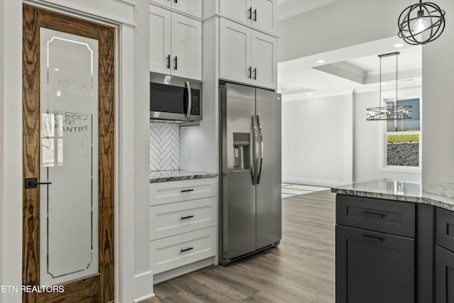 kitchen with crown molding, appliances with stainless steel finishes, white cabinetry, hanging light fixtures, and light wood-type flooring