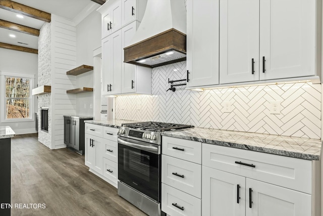 kitchen with custom exhaust hood, white cabinetry, stainless steel gas range oven, decorative backsplash, and beamed ceiling