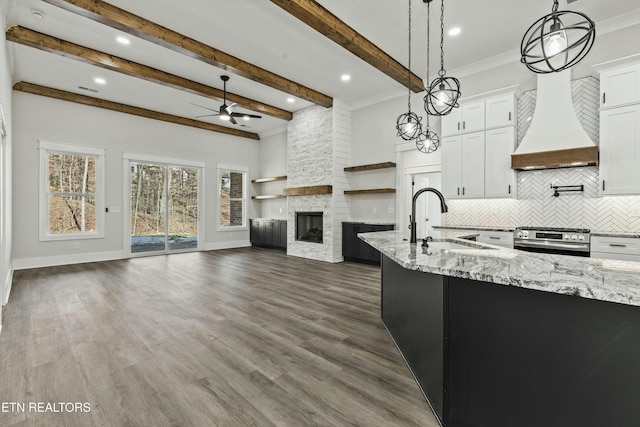 kitchen featuring sink, decorative light fixtures, white cabinetry, and gas range