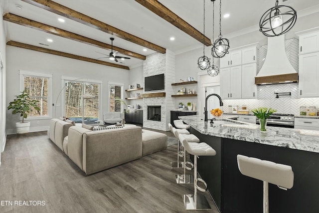 kitchen with white cabinets, decorative light fixtures, sink, dark hardwood / wood-style flooring, and a breakfast bar