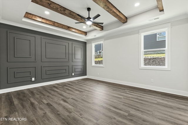 empty room with ceiling fan, a raised ceiling, beam ceiling, and dark wood-type flooring