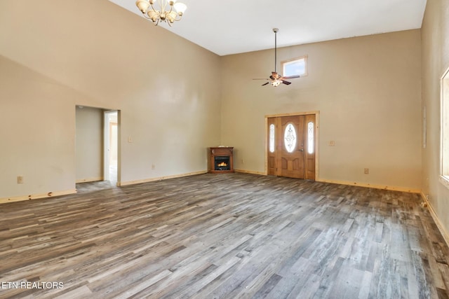 entryway with ceiling fan with notable chandelier, hardwood / wood-style floors, and high vaulted ceiling