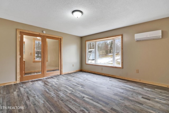 empty room featuring a textured ceiling, dark hardwood / wood-style floors, a wall mounted AC, and a healthy amount of sunlight