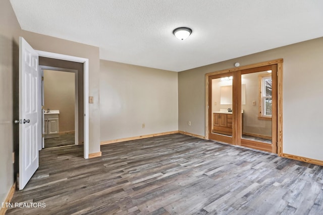 spare room featuring a textured ceiling and dark hardwood / wood-style floors