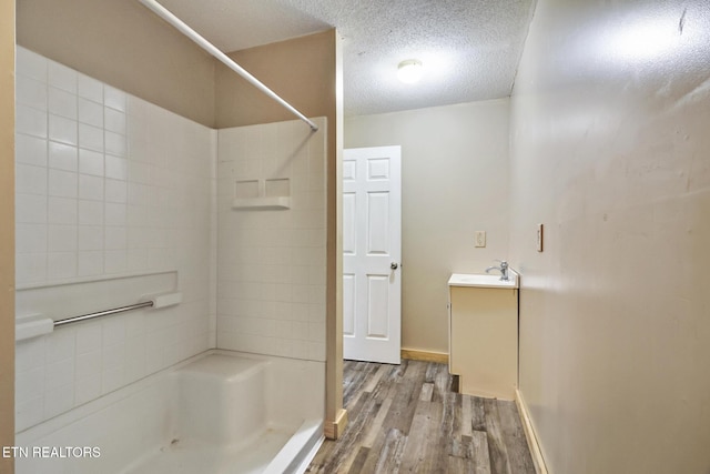 bathroom featuring a textured ceiling, walk in shower, hardwood / wood-style flooring, and vanity