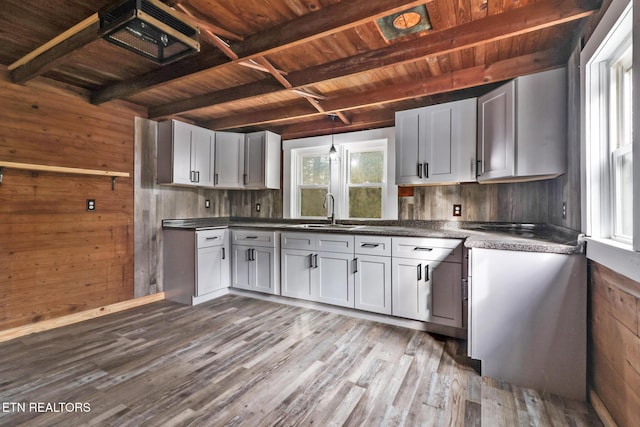 kitchen featuring wood walls, sink, beamed ceiling, hanging light fixtures, and dark hardwood / wood-style flooring