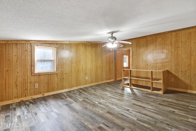 spare room with ceiling fan, dark wood-type flooring, and wooden walls