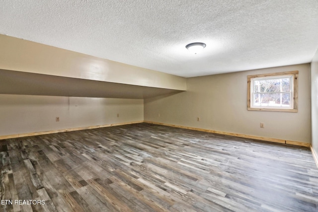 additional living space with a textured ceiling and dark hardwood / wood-style flooring