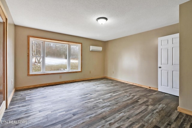 spare room featuring a textured ceiling, dark hardwood / wood-style floors, and an AC wall unit