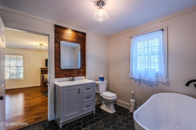 bathroom featuring toilet, vanity, a tub to relax in, hardwood / wood-style flooring, and ornamental molding