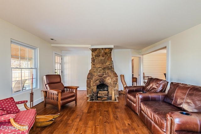 living room with dark hardwood / wood-style floors and a stone fireplace