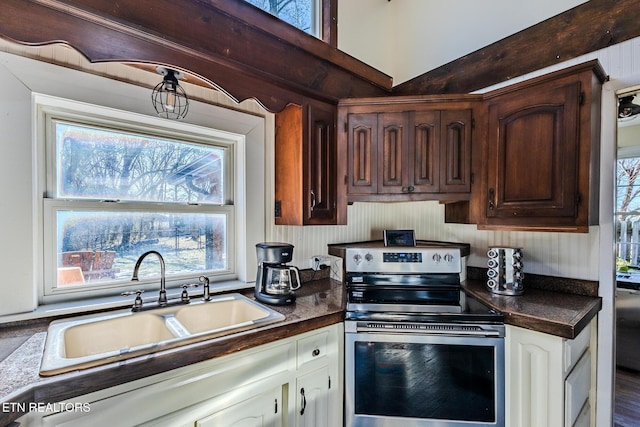 kitchen with stainless steel range with electric cooktop, white cabinets, dark brown cabinetry, and sink