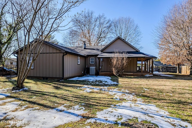 snow covered rear of property featuring a lawn and central air condition unit