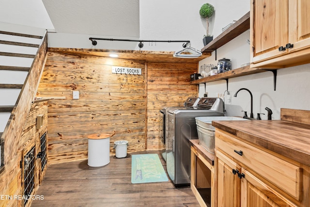 clothes washing area featuring wooden walls, washer and dryer, wood-type flooring, a textured ceiling, and cabinets