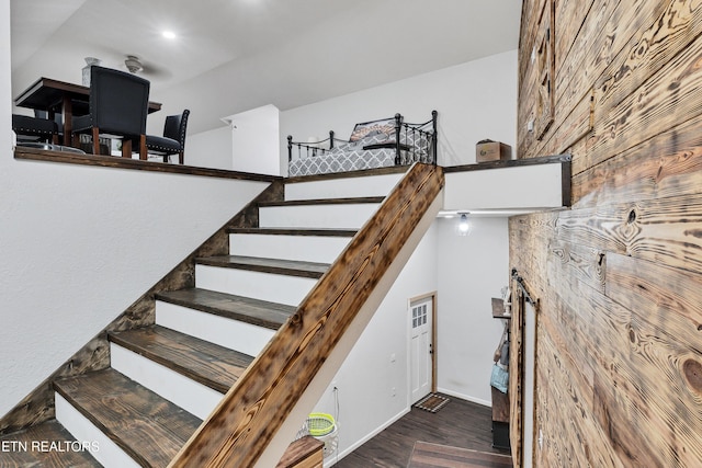 stairs featuring hardwood / wood-style flooring and wooden walls