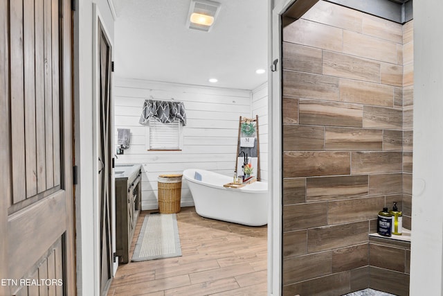 bathroom featuring wood walls, a washtub, and vanity