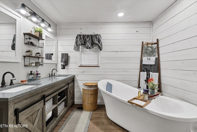 bathroom featuring a bath, wood-type flooring, wood walls, and vanity