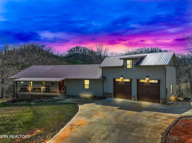 view of front of home with metal roof, stone siding, concrete driveway, and an attached garage