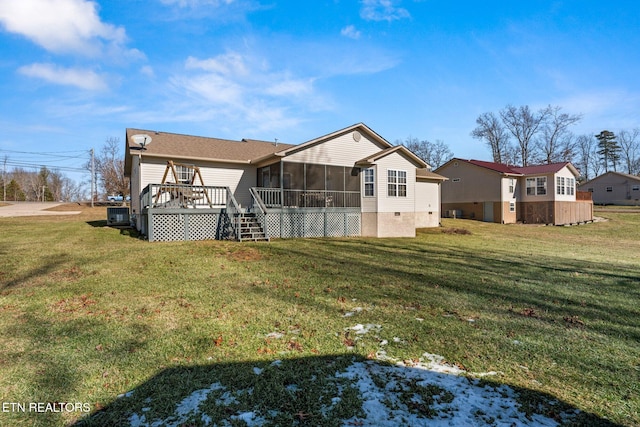 rear view of house featuring a wooden deck, a yard, and a sunroom