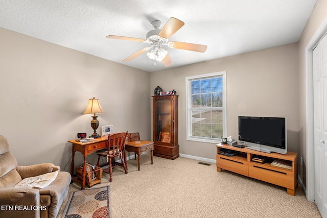 office featuring ceiling fan, a textured ceiling, and light carpet