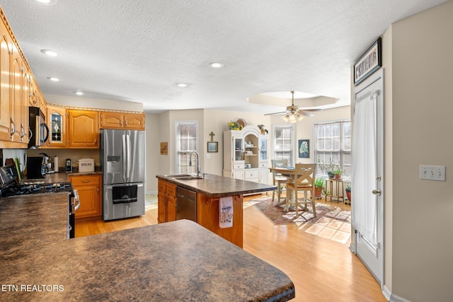 kitchen featuring sink, appliances with stainless steel finishes, a kitchen island with sink, and light wood-type flooring