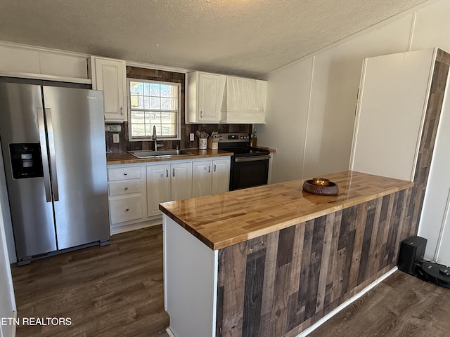 kitchen featuring wood counters, appliances with stainless steel finishes, a textured ceiling, white cabinets, and sink