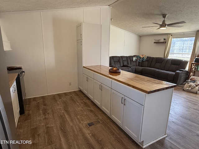 kitchen with ceiling fan, dark wood-type flooring, a textured ceiling, white cabinets, and butcher block counters