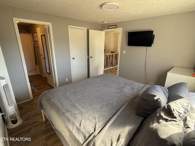 bedroom with a textured ceiling and dark hardwood / wood-style floors