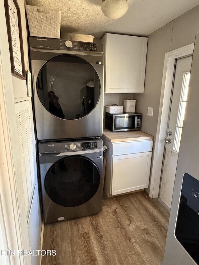 laundry room featuring light hardwood / wood-style floors, a textured ceiling, and stacked washer / drying machine