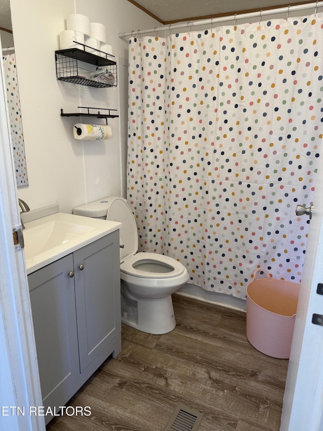 bathroom with toilet, wood-type flooring, walk in shower, ornamental molding, and vanity