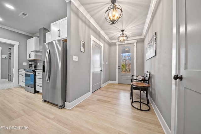 kitchen with white cabinets, wall chimney exhaust hood, stainless steel appliances, an inviting chandelier, and hanging light fixtures