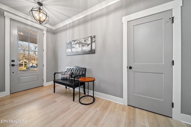 foyer featuring crown molding, light wood-type flooring, and an inviting chandelier